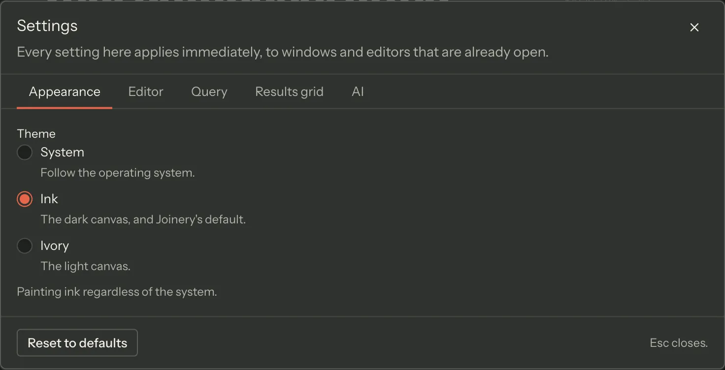 The settings dialog on its Appearance tab, with Editor, Query, Results grid and AI beside it: the Theme radios — System, Ink and Ivory, each with the app’s own one-line description of the mode — Ink selected, a line naming how the choice currently resolves, and Reset to defaults along the foot.